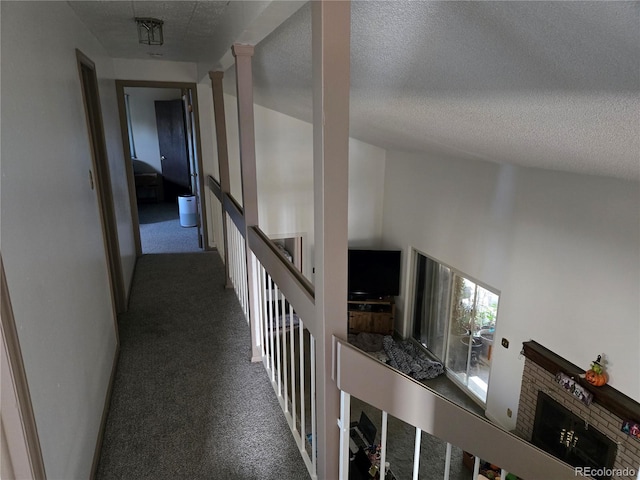 corridor with dark colored carpet, a towering ceiling, and a textured ceiling