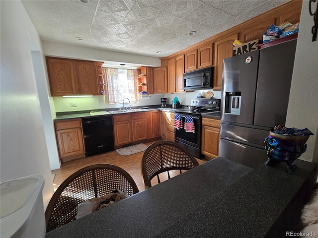 kitchen with sink, light hardwood / wood-style flooring, and black appliances