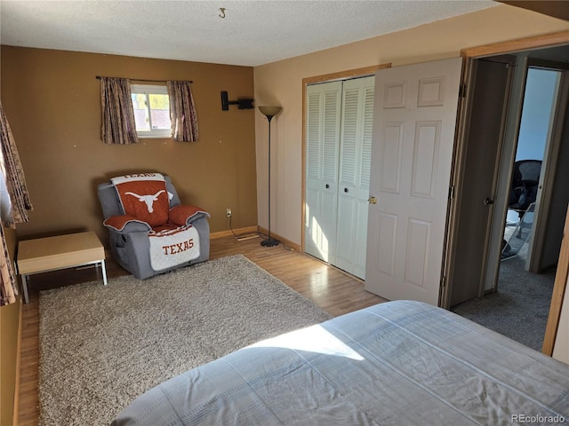 bedroom with a textured ceiling, hardwood / wood-style flooring, and a closet