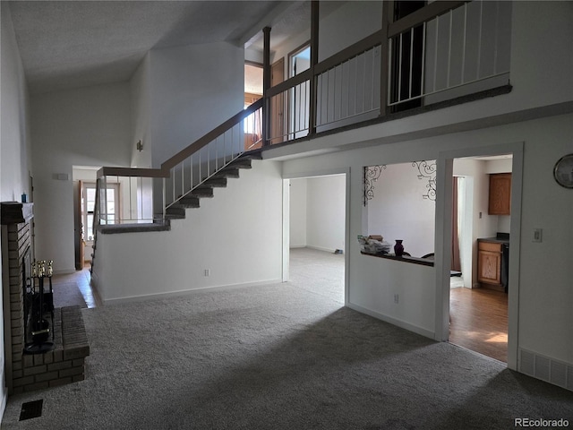 unfurnished living room featuring carpet floors, a fireplace, and high vaulted ceiling