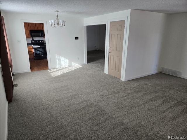 spare room with a notable chandelier, dark carpet, and a textured ceiling