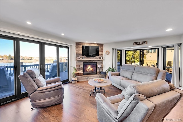 living room featuring hardwood / wood-style floors, a water view, and a fireplace