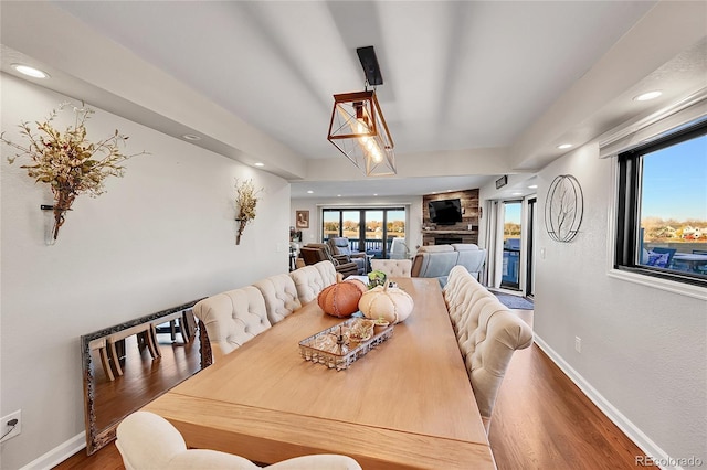 dining area featuring hardwood / wood-style flooring and a stone fireplace