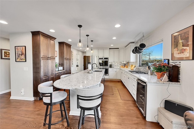 kitchen featuring beverage cooler, a breakfast bar area, decorative backsplash, white cabinets, and appliances with stainless steel finishes