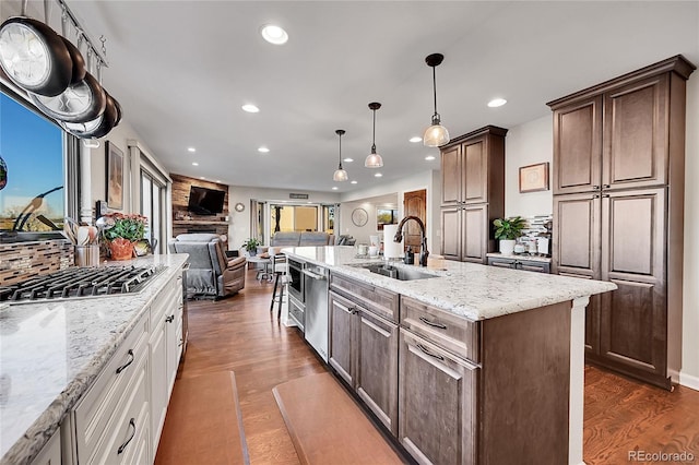 kitchen featuring white cabinetry, sink, stainless steel appliances, dark hardwood / wood-style flooring, and a center island with sink