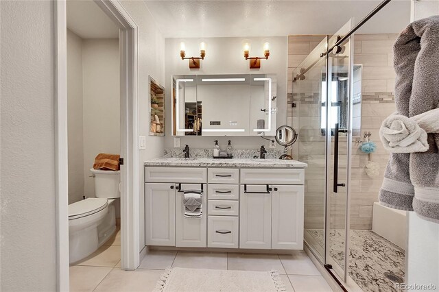 bathroom with tile patterned floors, vanity, an enclosed shower, and toilet