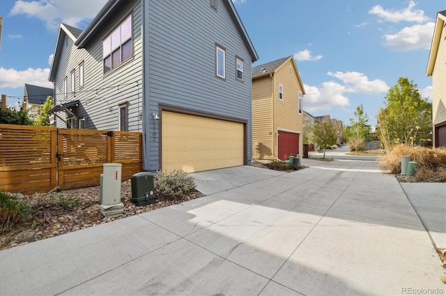 1702 W 66th Ave, Denver, CO 80221 - view of side of property with fence, an attached garage, and concrete driveway