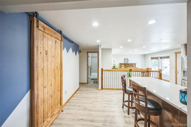 10462 Hoyt St, Westminster, CO 80021 - kitchen with light wood-type flooring, stainless steel fridge with ice dispenser, a barn door, recessed lighting, and a kitchen bar