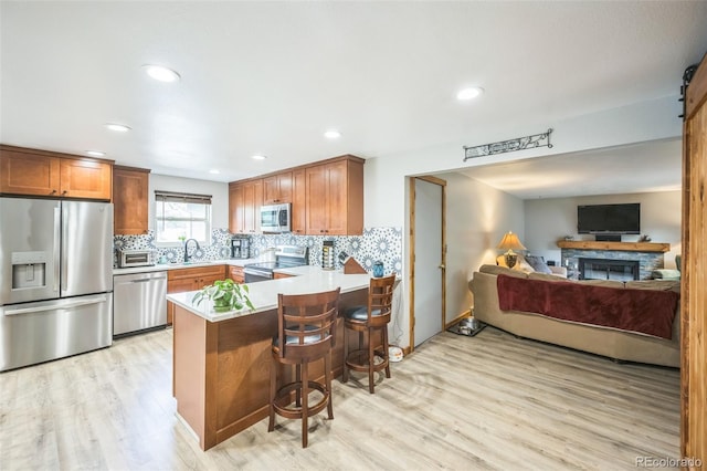 10462 Hoyt St, Westminster, CO 80021 - kitchen featuring appliances with stainless steel finishes, a peninsula, light wood-style flooring, open floor plan, and decorative backsplash