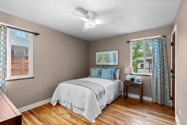bedroom with multiple windows, light wood-type flooring, and baseboards