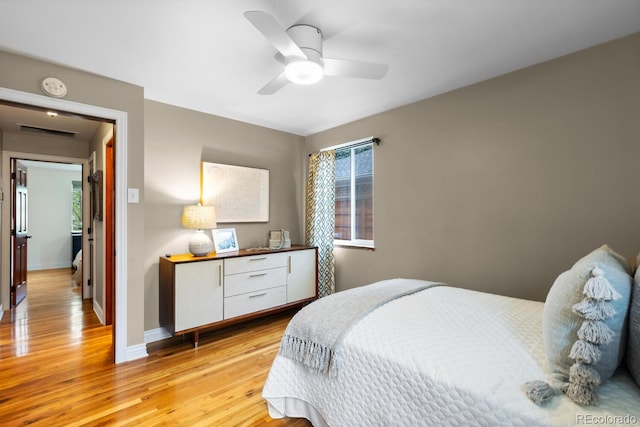 bedroom with light wood-style floors, baseboards, and ceiling fan
