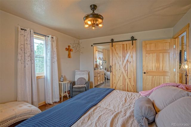 bedroom featuring hardwood / wood-style floors, ensuite bathroom, and a barn door