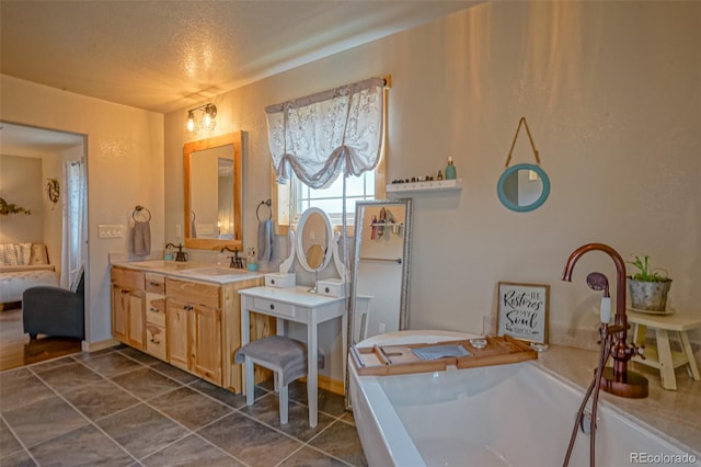 bathroom with vanity, tile patterned flooring, a bathing tub, and a textured ceiling