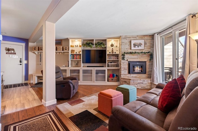 living room with hardwood / wood-style floors, built in shelves, and a fireplace