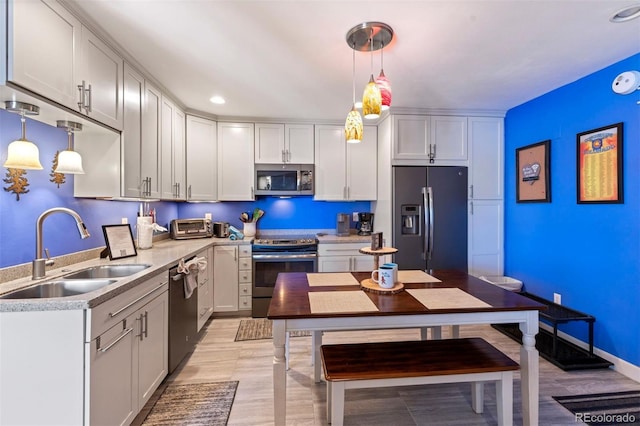 kitchen featuring stainless steel appliances, pendant lighting, white cabinets, and sink