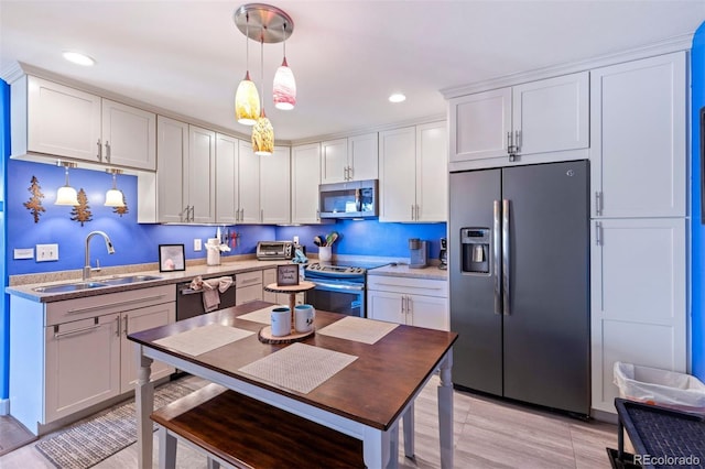 kitchen with hanging light fixtures, sink, stainless steel appliances, and white cabinetry