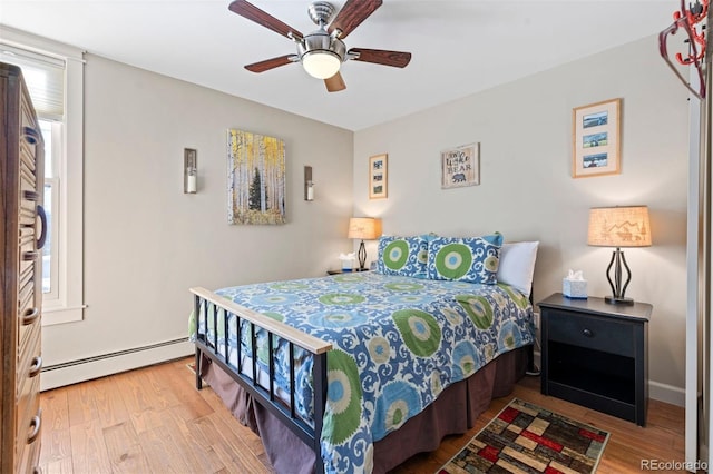 bedroom with baseboard heating, hardwood / wood-style floors, and ceiling fan