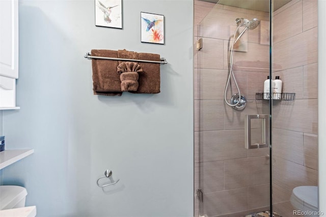 bathroom featuring a shower with shower door and toilet