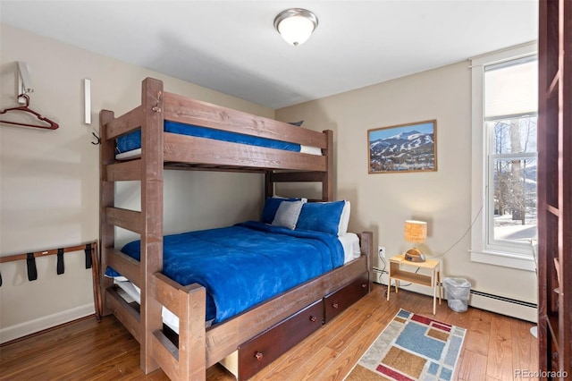 bedroom featuring a baseboard heating unit and wood-type flooring