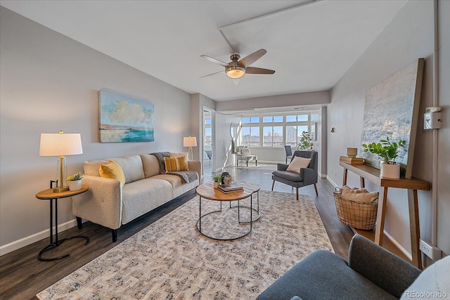 living room with ceiling fan, baseboards, and dark wood finished floors