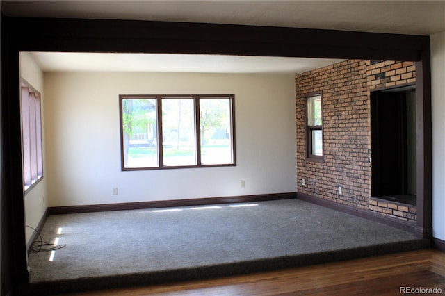 empty room with beamed ceiling and brick wall