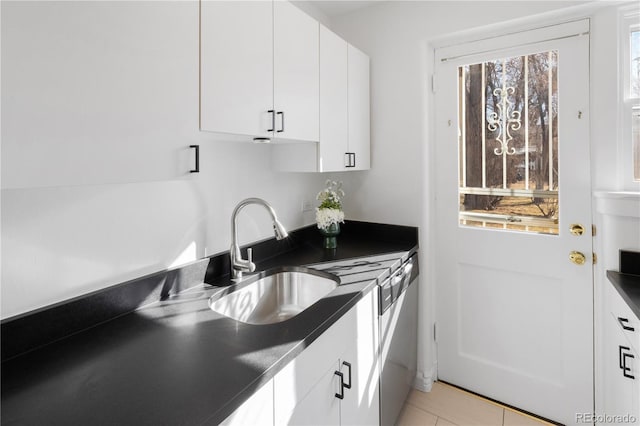 kitchen featuring white cabinetry, dark countertops, light tile patterned floors, and a sink