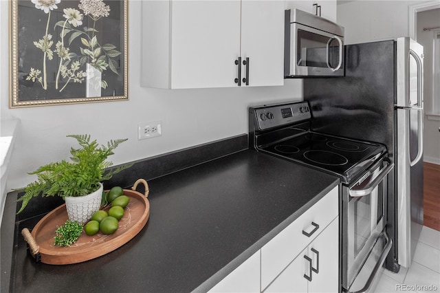 kitchen featuring dark countertops, appliances with stainless steel finishes, tile patterned flooring, and white cabinetry