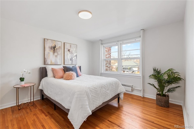 bedroom with light wood finished floors, baseboards, and a baseboard radiator