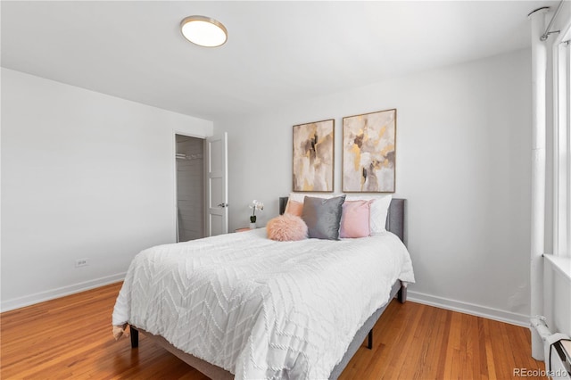 bedroom with a closet, baseboards, and wood finished floors