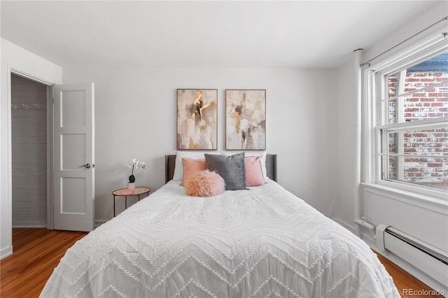 bedroom with a baseboard heating unit and wood finished floors