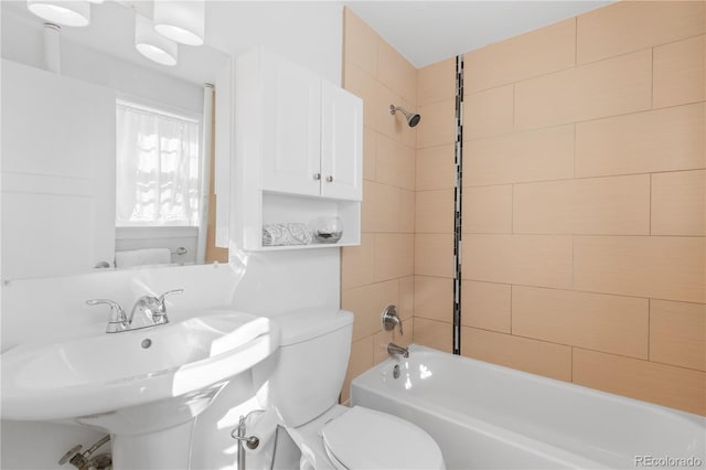 bathroom with toilet, washtub / shower combination, and a sink