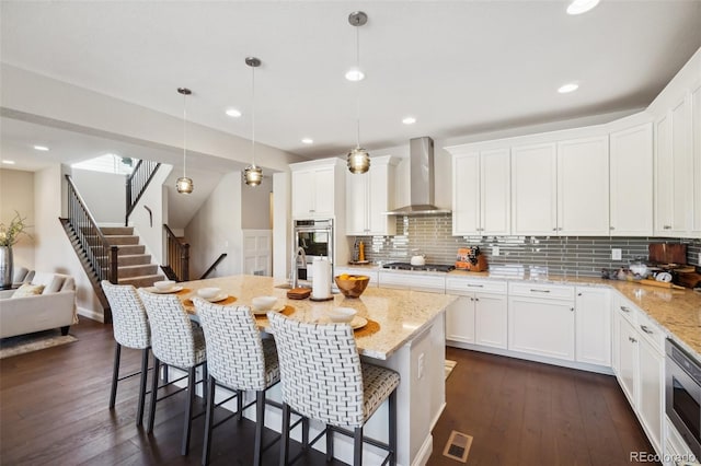 kitchen featuring dark wood-style floors, appliances with stainless steel finishes, wall chimney exhaust hood, and white cabinets