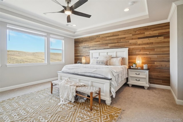 bedroom with baseboards, crown molding, wood walls, a raised ceiling, and light colored carpet