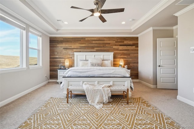 bedroom with a tray ceiling, light carpet, wooden walls, and an accent wall