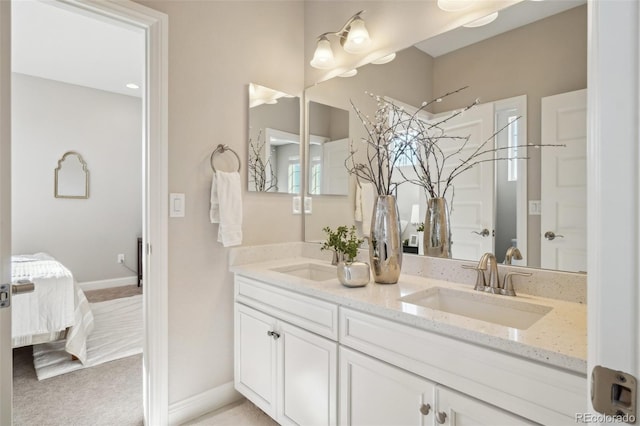 full bath featuring a sink, connected bathroom, baseboards, and double vanity