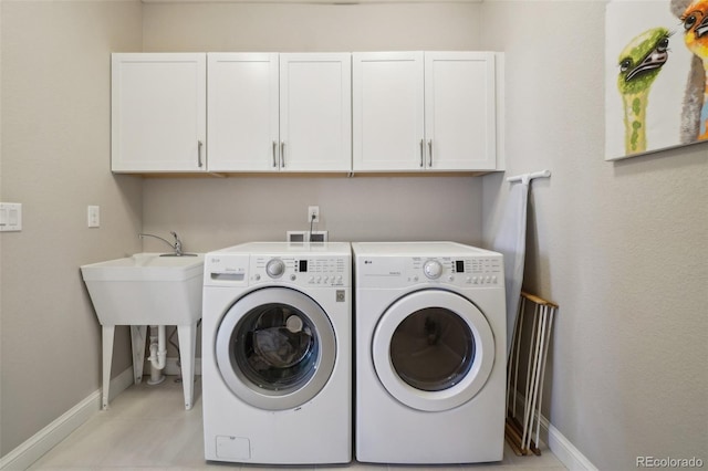 laundry room featuring light tile patterned floors, baseboards, cabinet space, and washing machine and dryer