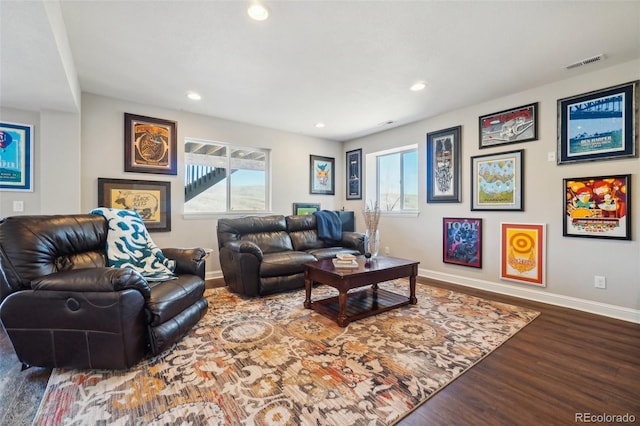 living area featuring a wealth of natural light, visible vents, baseboards, and wood finished floors