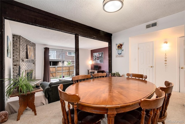 dining space with beam ceiling, carpet floors, and a textured ceiling