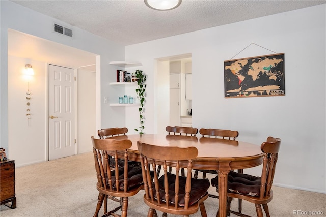 carpeted dining area with a textured ceiling