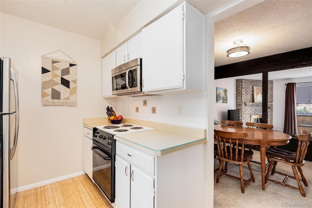 kitchen featuring white cabinetry, beam ceiling, stainless steel appliances, a textured ceiling, and light hardwood / wood-style flooring