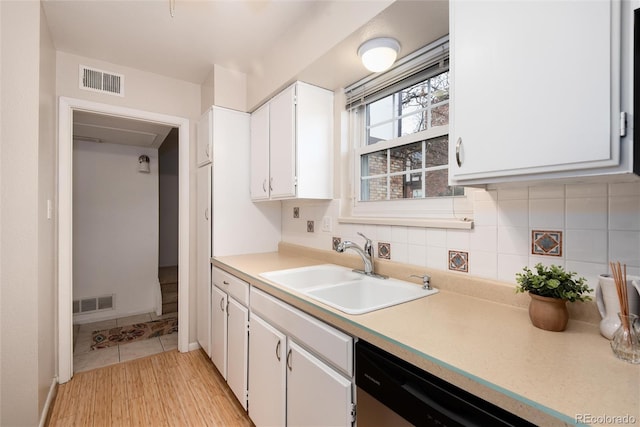 kitchen featuring sink, tasteful backsplash, light hardwood / wood-style flooring, dishwasher, and white cabinets