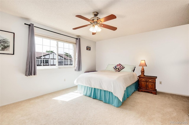 carpeted bedroom featuring ceiling fan and a textured ceiling