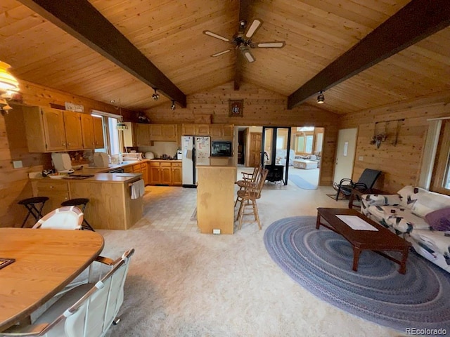 interior space featuring ceiling fan, white fridge, lofted ceiling with beams, kitchen peninsula, and wood walls