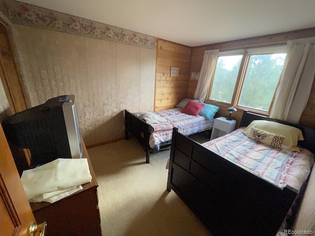 bedroom featuring light carpet and wood walls