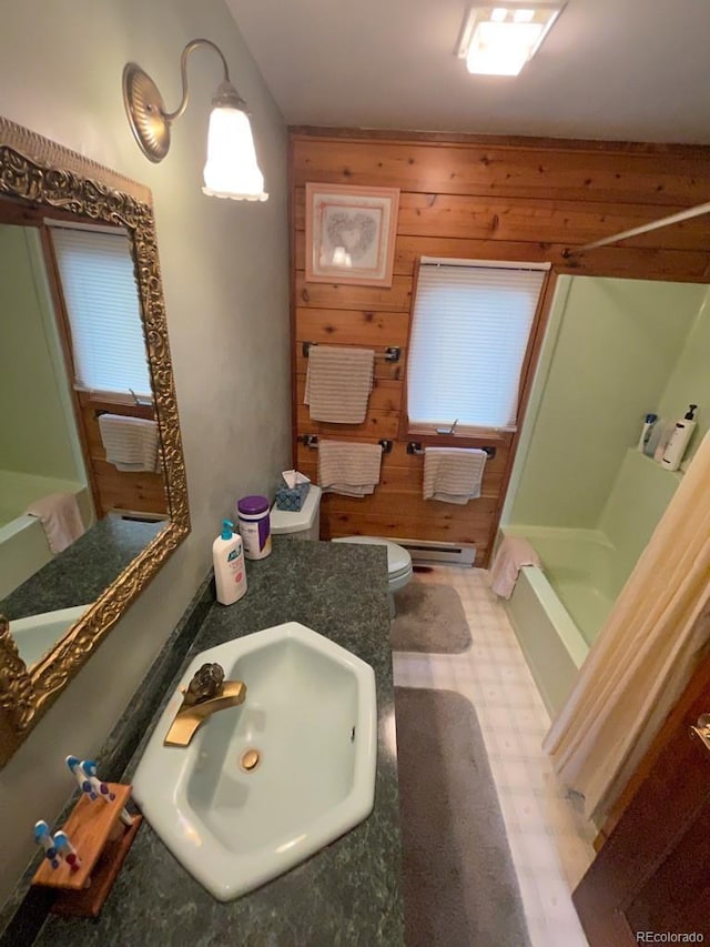 bathroom featuring sink, wooden walls, a baseboard radiator, and toilet