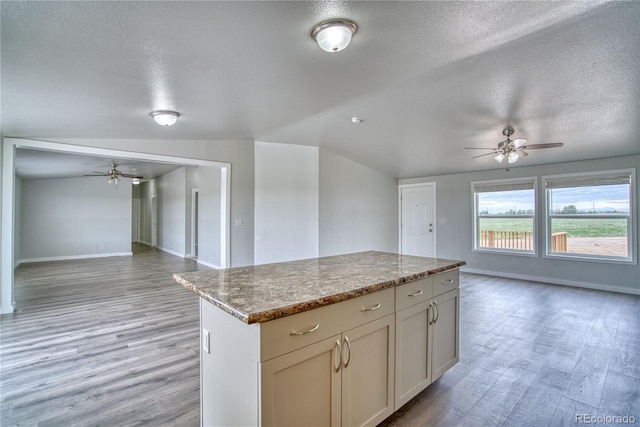15660 County Road 49, La Salle, CO 80645 - kitchen with open floor plan, a ceiling fan, a textured ceiling, a kitchen island, and light wood-style floors