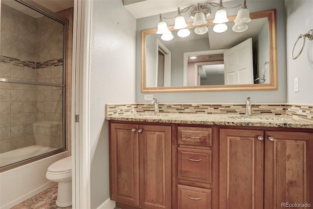 bathroom featuring shower / bath combination with glass door, a sink, toilet, and decorative backsplash