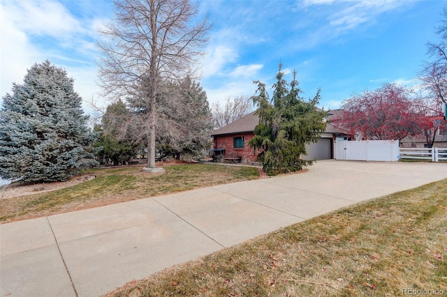 view of front facade with a garage, concrete driveway, fence, a front yard, and brick siding