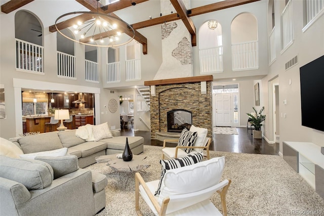 living room with a chandelier, a stone fireplace, wood finished floors, visible vents, and baseboards