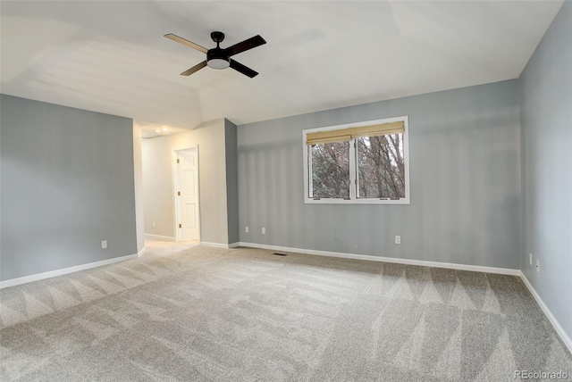 carpeted empty room featuring ceiling fan, visible vents, baseboards, and vaulted ceiling